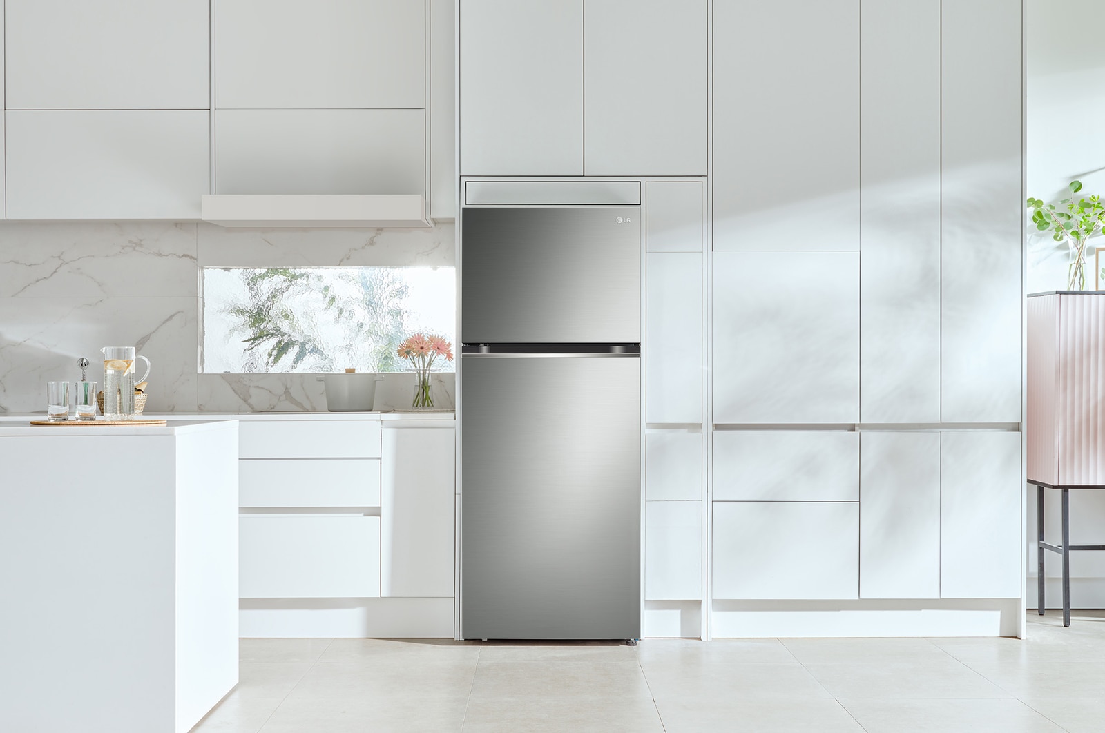 Le réfrigérateur à congélateur supérieur LG LT13C2000V de 28 po et 13 pi³ au fini inoxydable, encastré dans une cuisine blanche moderne et lumineuse.