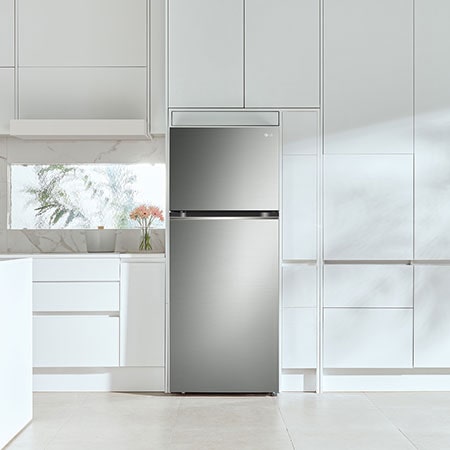 Le réfrigérateur à congélateur supérieur LG LT13C2000V de 28 po et 13 pi³ au fini inoxydable, encastré dans une cuisine blanche moderne et lumineuse.