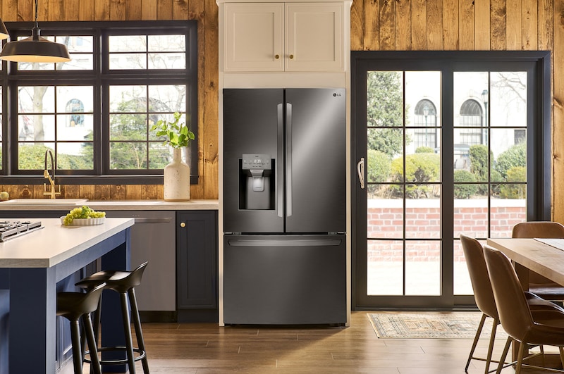 Le réfrigérateur à portes françaises LG LRFS28XBD de 36 po et 28 pi³ en acier inoxydable noir PrintProof™ avec distributeur d'eau, présenté dans une cuisine aux tons chauds.