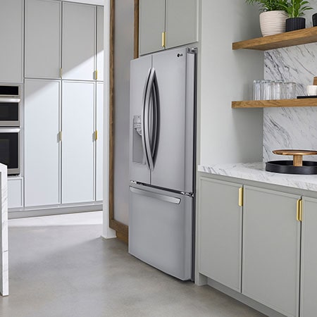 Le réfrigérateur à portes françaises LG LRFS28XBS de 36 po et 28 pi³ en acier inoxydable PrintProof™ avec distributeur de glace et d'eau, présenté dans une cuisine moderne et lumineuse.
