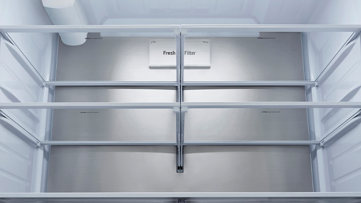 Vue intérieure d'un réfrigérateur avec étagères en verre et panneau arrière en acier inoxydable avec filtre à air.