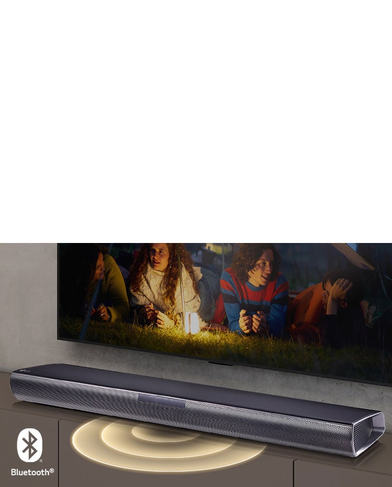 Un téléviseur de LG est fixé au mur. L’écran montre deux couples allongés dans l’herbe. Devant eux, il y a une lampe. La barre de son LG est sous le téléviseur de LG. Le graphique sonore sort de l’avant de la barre de son. Le logo Bluetooth est dans le coin inférieur gauche de l’image.