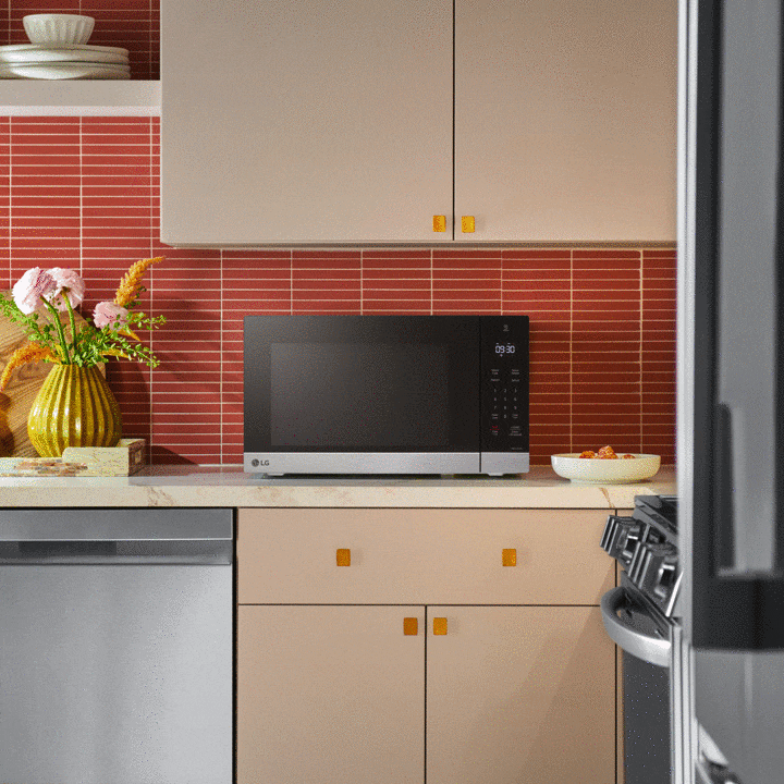 Intérieur d'un four à micro-ondes LG en acier inoxydable avec éclairage LED lumineux et plateau tournant en verre.