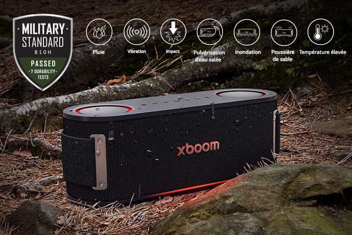xboom Bounce is placed on soil covered with wet leaves, between a tree root and a stone. On the above left side Military standard logo is placed.	