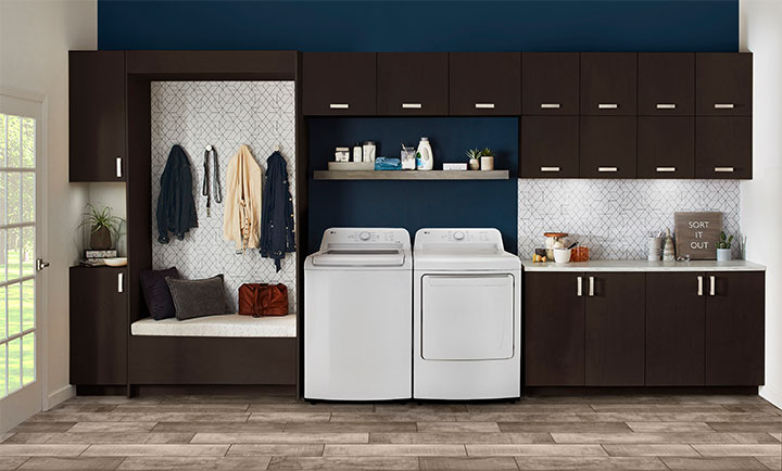 Buanderie moderne avec lave-linge et sèche-linge blancs, armoires brun foncé et banquette intégrée.
