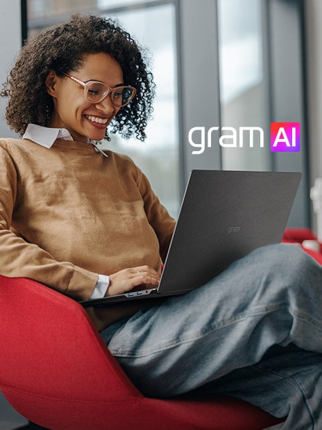 Une personne assise confortablement dans une chaise moderne, travaillant sur un ordinateur portable LG Gram avec un sourire. Le logo gram AI est affiché de manière visible sur l'image.
