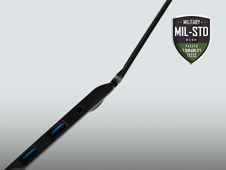 Cette image montre le côté gauche d'un ordinateur portable ouvert, mettant en avant son design mince. Dans le coin supérieur droit, le logo MIL-STD est visible.