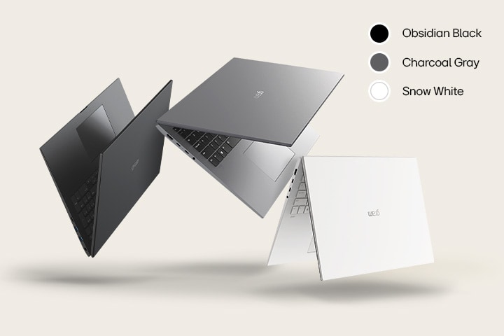 Trois ordinateurs portables dans différentes couleurs : Noir Obsidien, Gris Charbon et Blanc Neige, disposés de manière dynamique sur un fond beige.