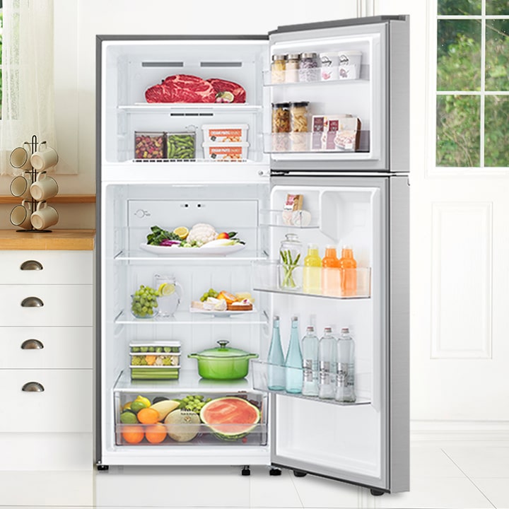 Réfrigérateur à congélateur supérieur LG en acier inoxydable, portes fermées, dans une cuisine moderne.