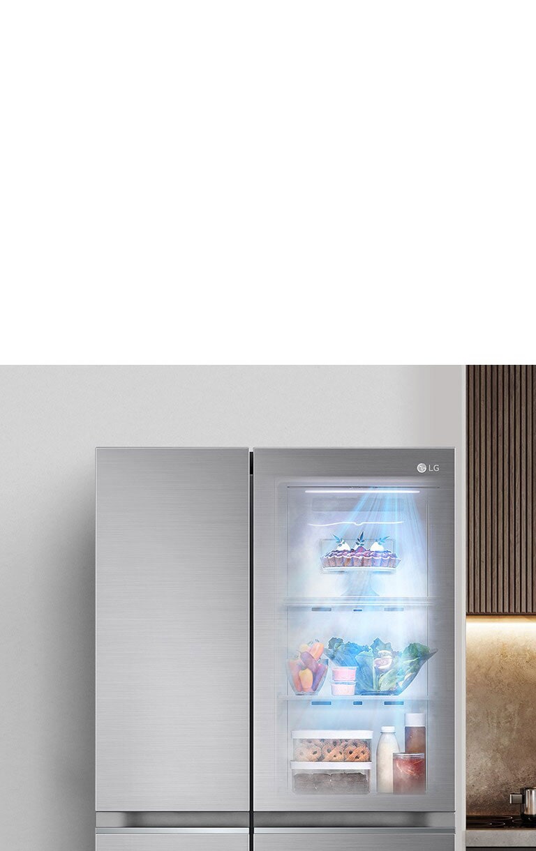 Réfrigérateur LG avec porte vitrée illuminée, montrant des aliments frais, intégré dans une cuisine moderne.