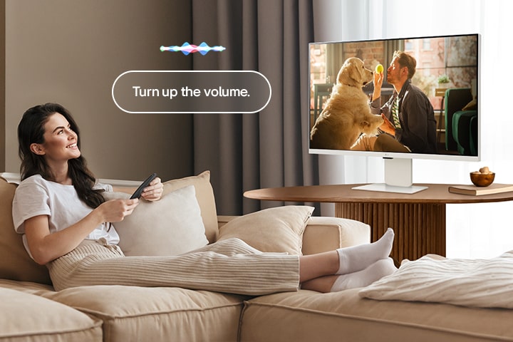Une femme augmente le volume du LG Smart Monitor à l’aide d’un Magic Remote.