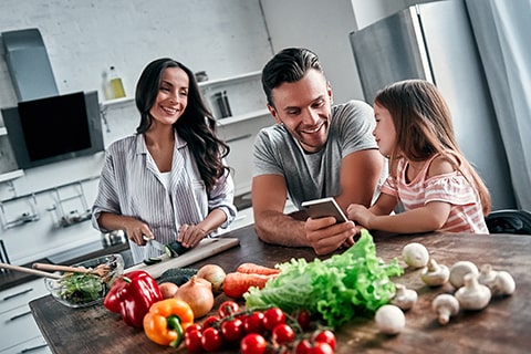 Une famille utilise l’application ThinQMD de LG pour commander ses électroménagers intelligents, montrant la synchronisation de la surface de cuisson à induction avec d’autres appareils de LG pour une commodité et une automatisation accrues.