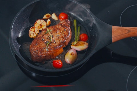 Des accessoires de cuisine sont placés sur une surface de cuisson à induction, démontrant l’utilisation de matériaux magnétiques comme la fonte et l’acier inoxydable magnétique pour permettre le bon fonctionnement de l’induction.