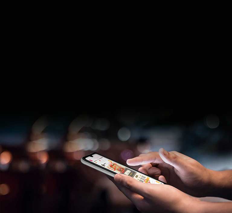 Une main tient le téléphone LG AristoMD 5 et navigue entre les applications.