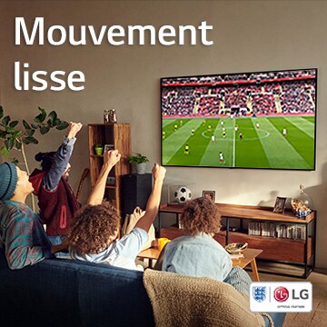 Quatre personnes sont assises sur un canapé dans un salon à regarder une partie de soccer.