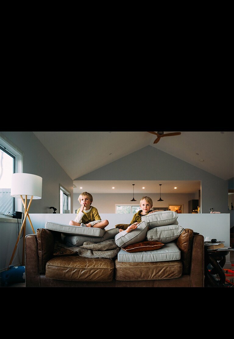 Deux garçons jumeaux regardent quelque chose assis sur un canapé.