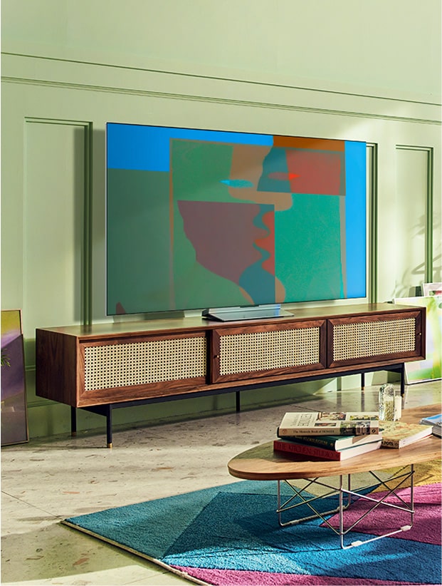 Un téléviseur OLED de LG sur socle pivotant se trouve dans un salon coloré avec des meubles en bois et des plantes. Un téléviseur OLED de LG sur socle pivotant se trouve dans une pièce grise et abstraite