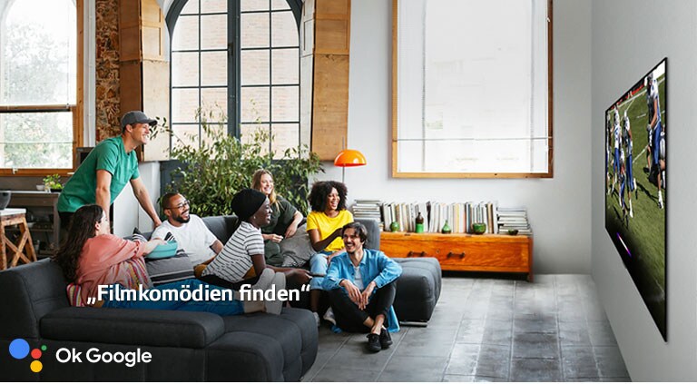 Eine Frau, die sich mit Freunden ein Fußballspiel im Fernsehen ansieht, bittet den Google Assistant, ihr eine Filmkomödie herauszusuchen.