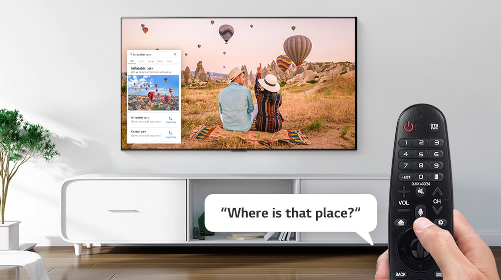 Nahaufnahme einer Hand, die den Fernseher mit einer Fernbedienung steuert, um zu erfahren, wo sich der im Fernsehen gezeigte Ort befindet.