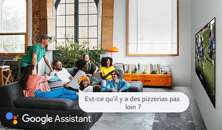 Une femme regarde du football avec des amis et demande à l’Assistant Google s’il y a des pizzerias pas loin