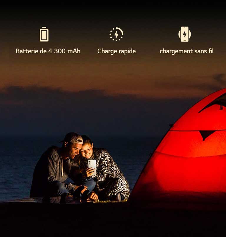 Un couple face à une tente la nuit.