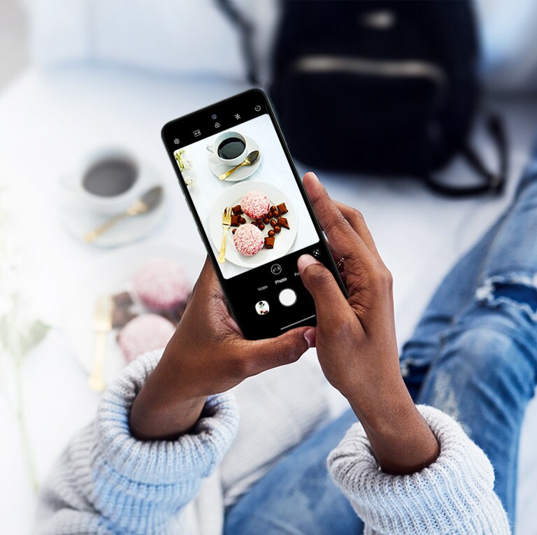 Une femme assise sur un canapé prend une photo.