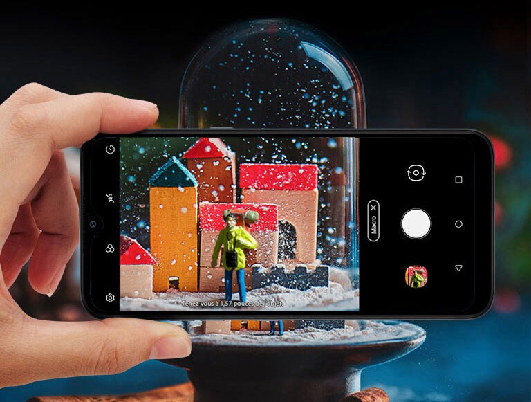 Gros plan d’une personne tenant un smartphone en train de prendre une photo d’une boule de neige