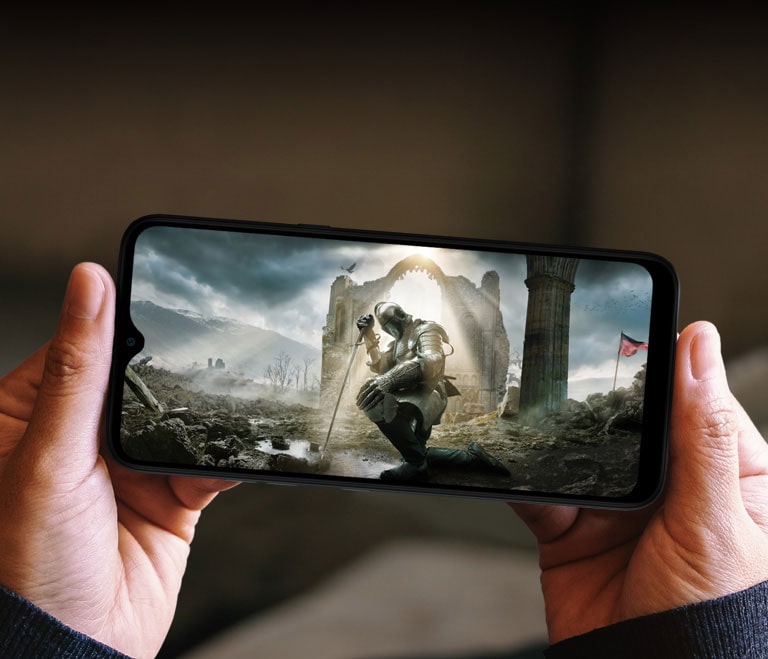 Une femme tenant un smartphone à deux mains et regardant un film se déroulant au moyen-âge