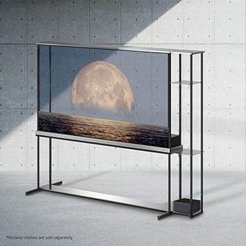 La LG SIGNATURE OLED T affiche une lune représentée au-dessus d’une rive sur l’écran transparent. La LG SIGNATURE OLED T se trouve au milieu d’une pièce avec une vue latérale sur la falaise qui donne sur la mer. Sur la droite se trouve un lit et une chaise longue. 