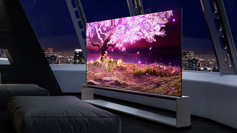 Un téléviseur affichant un arbre rose brillant est placé dans un salon sombre, la nuit.