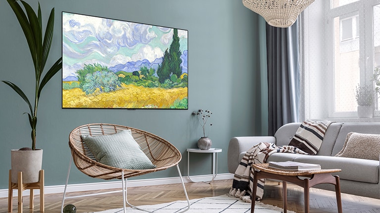 Un téléviseur affichant un objet artistique est accroché à un mur vert dans un salon avec une chaise, un canapé, et un pot de fleurs.