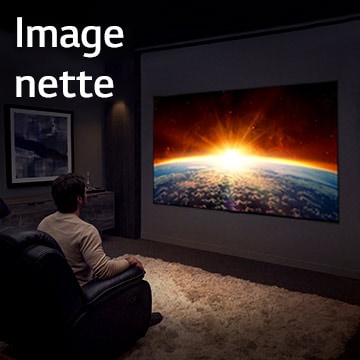 Un homme assis sur un canapé dans une pièce sombre regarde le téléviseur qui affiche le soleil se couchant derrière la Terre.