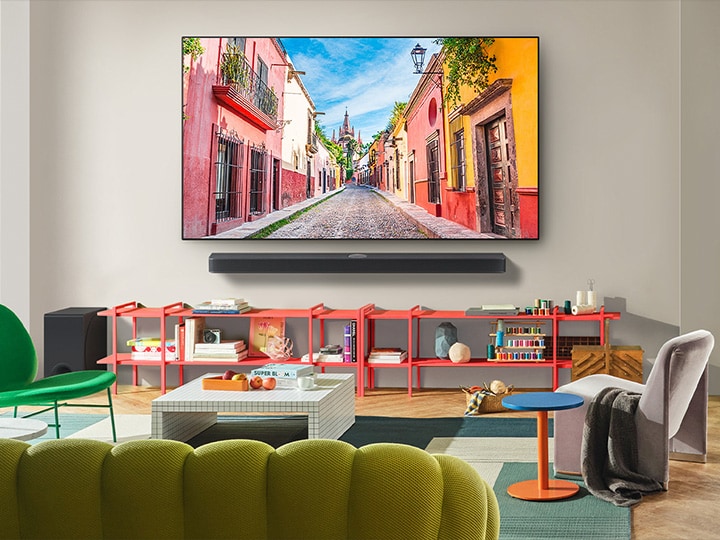 Vista de frente de la LG OLED TV montada en la pared con una Soundbar en una colorida sala de estar que muestra su diseño delgado y cómo se integra perfectamente en el entorno. 