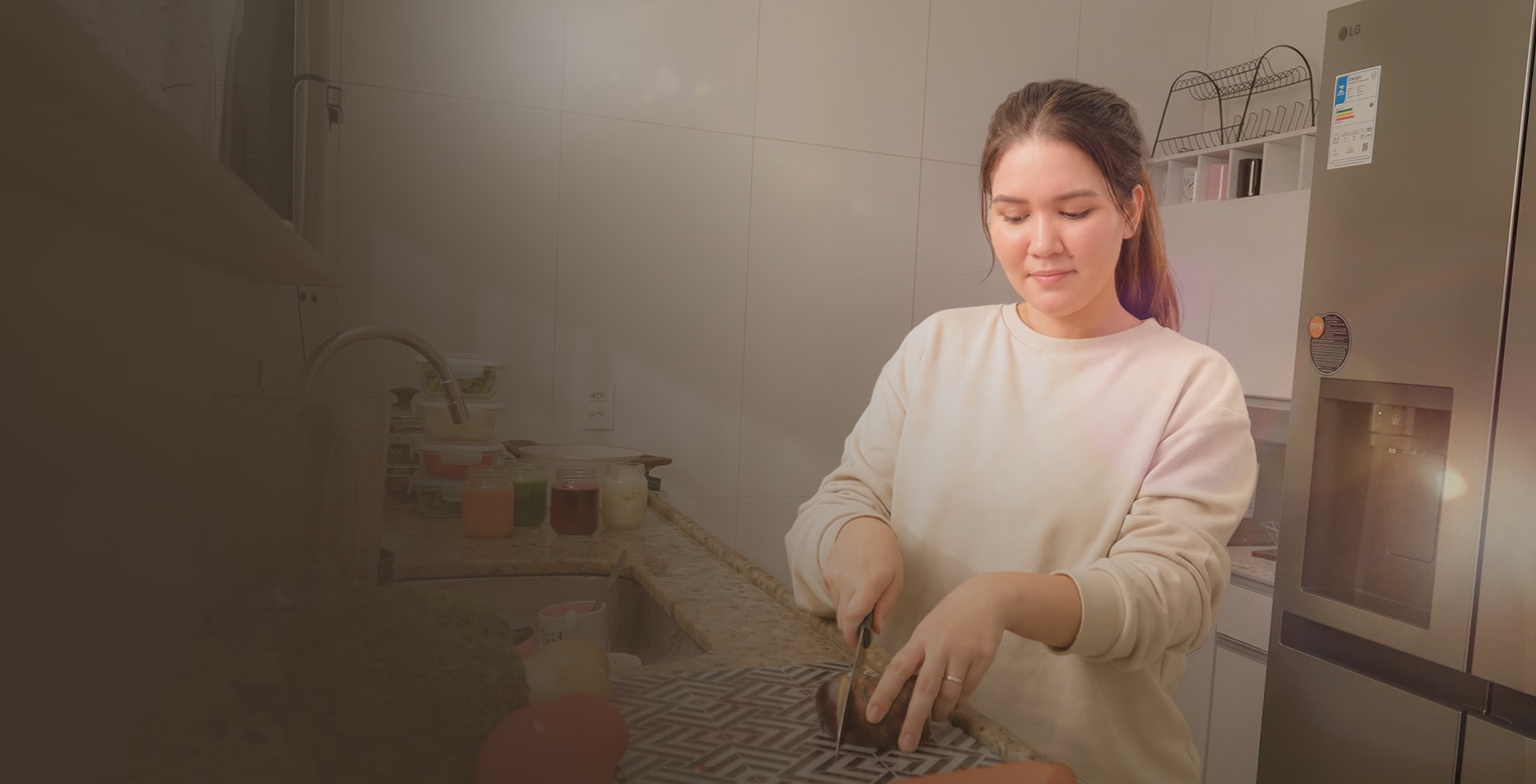 mamá cortando alimentos sobre la encimera de la cocina, junto a una nevera LG.
