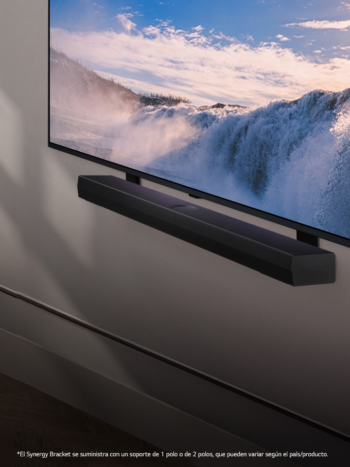 LG TV y LG Soundbar montados en la pared y ubicados dentro de una perspectiva inclinada. En el televisor, se muestra el primer plano de una enorme cascada, y tenue luz solar cae por la pared, el televisor y la soundbar. Aviso legal: “El Synergy Bracket se suministra con un soporte de 1 polo o de 2 polos, que pueden variar según el país/producto”.
