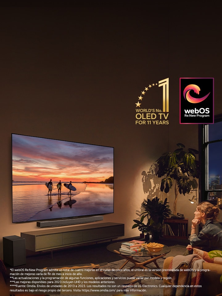 Televisor LG OLED evo C4 montado en la pared de una cálida sala de estar nocturna y una LG soundbar montada justo debajo. En el televisor, se muestra el atardecer en una playa con siluetas de tres surfistas. Dos mujeres están sentadas en el sofá inclinadas hacia el televisor y la barra de sonido. En la imagen se encuentra el emblema “OLED TV número 1 del mundo durante 11 años” y el logotipo “programa webOS Re:New”. Aviso legal: *El webOS Re:New Program admite un total de cuatro mejoras en el curso de cinco años, el umbral es la versión preinstalada de webOS, y la programación de mejoras varía de fin de mes a inicio de año”. “Las actualizaciones y la programación de algunas funciones, aplicaciones y servicios puede variar por modelo y región”. “Las mejoras disponibles para 2023 incluyen UHD y los modelos anteriores”. “Fuente: Omdia. Envíos de unidades de 2013 a 2023. Los resultados no son un respaldo de LG Electronics. Cualquier dependencia en estos resultados es bajo el riesgo propio del tercero. Visita https://www.omdia.com/ para más información”.