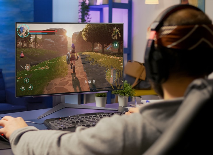 Persona jugando en un monitor LG con una escena de juego colorida en una habitación con poca luz.