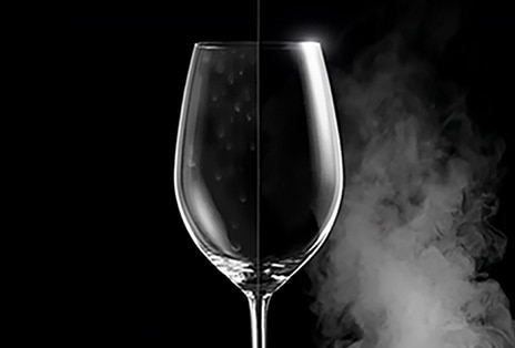 Una copa de vino con manchas de agua por un lado, y clara e impecable por el otro tras el lavado a vapor.