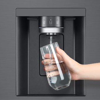 Una persona toma agua del dispensador del refrigerador en un vaso