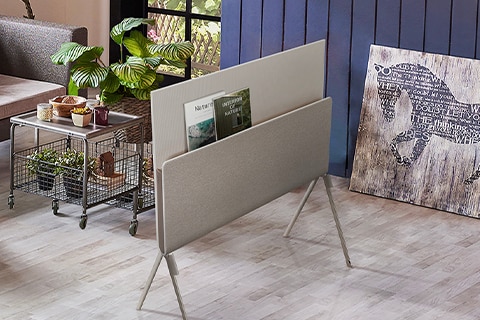Posé seen from the back with nature magazines placed on the media shelf in a plant-themed living room.