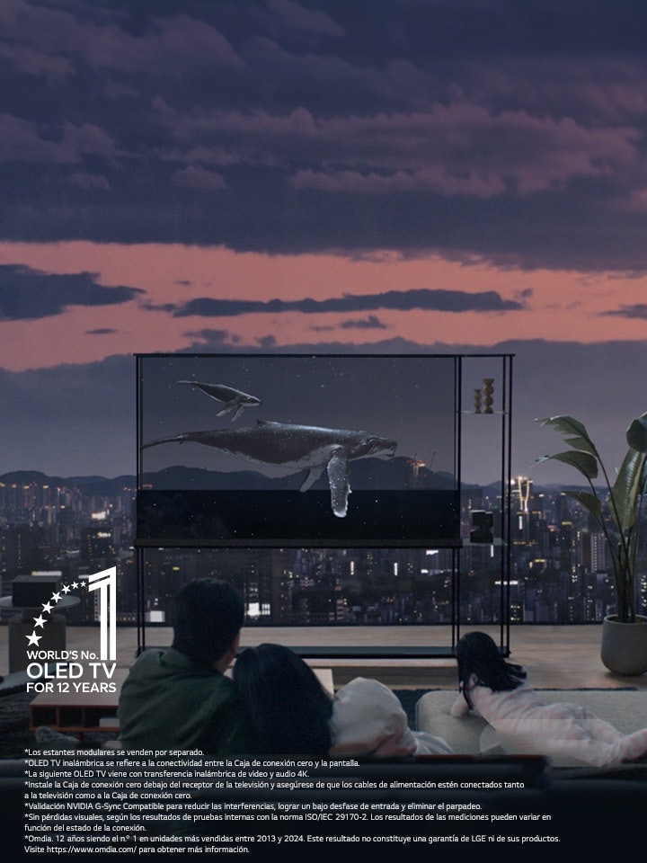 Una ballena nada por el LG SIGNATURE OLED T mientras la pantalla se oscurece para revelar el horizonte de la ciudad al anochecer. Personas sentadas en un sofá en primer plano frente a la televisión y una ventana. La Caja de conexión cero se encuentra en una mesita a la izquierda de la televisión.