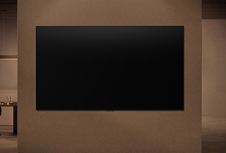 Una LG TV wall-mounted con la pantalla apagada muestra cómo los sensores de movimiento de la TV pueden ajustarse de forma inteligente en función del movimiento detectado cerca.
