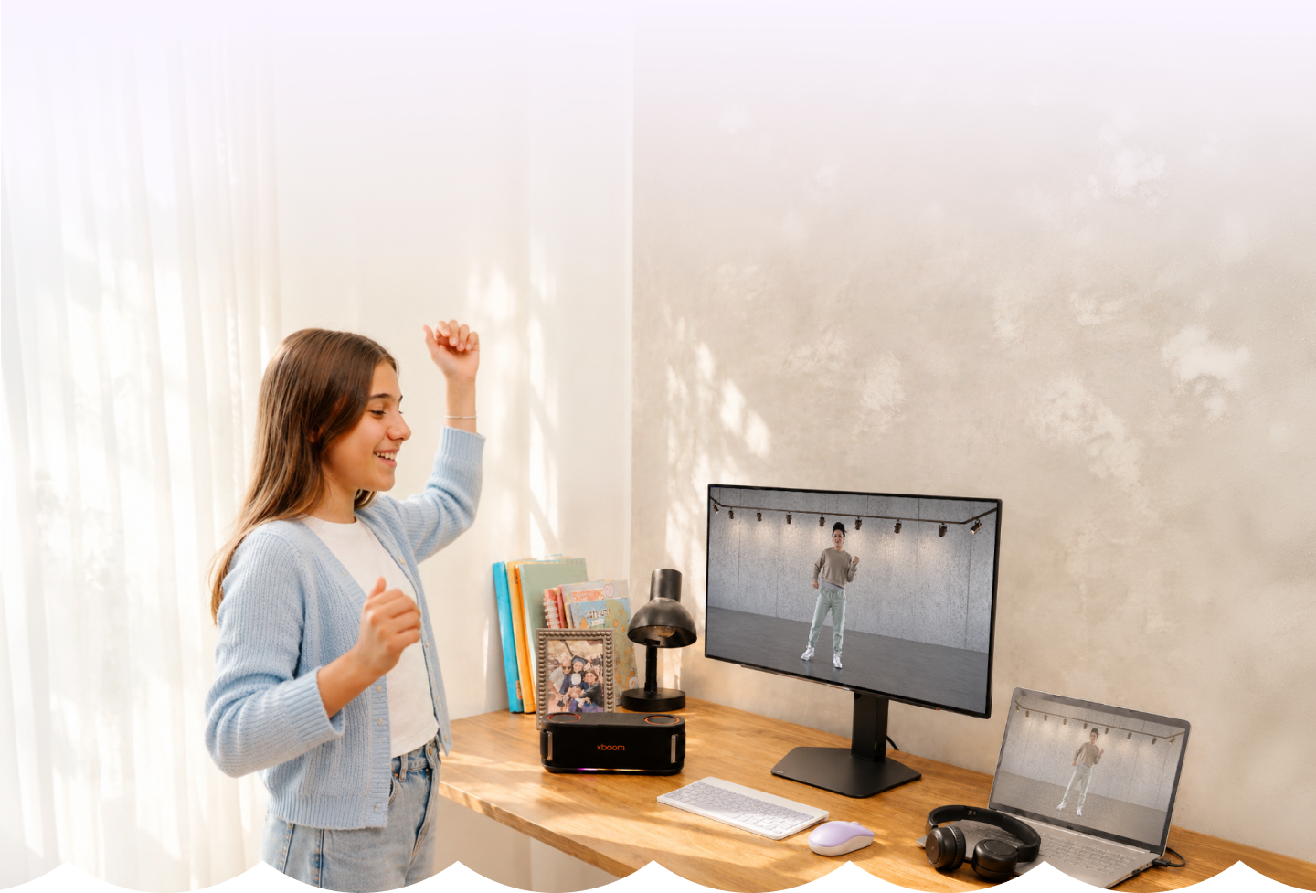Adolescente bailando un juego de ritmo en el monitor LG, con el parlante xboom y un portátil en el escritorio