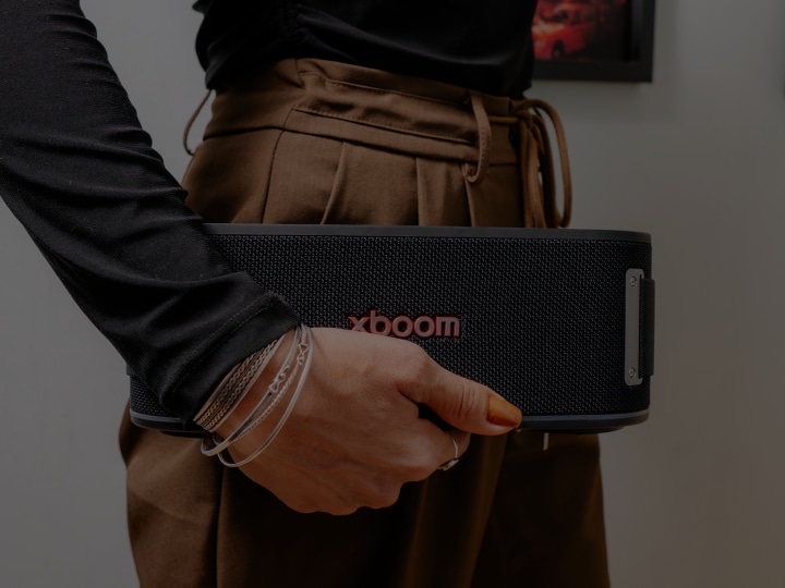 Primer plano de una mano sosteniendo un parlante portátil LG xboom