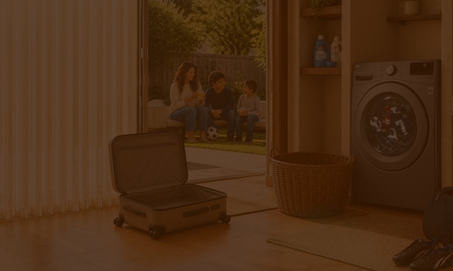 Familia sentada en el patio mientras una lavadora LG funciona en el interior del hogar, junto a una maleta, una cesta de ropa y artículos deportivos.