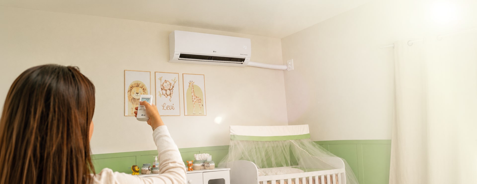 Una mamá ajusta el aire acondicionado LG de pared en la habitación del bebé.