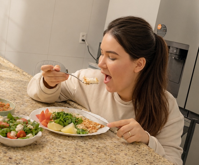 mamá comiendo en la mesa de la cocina, con una nevera LG al fondo.