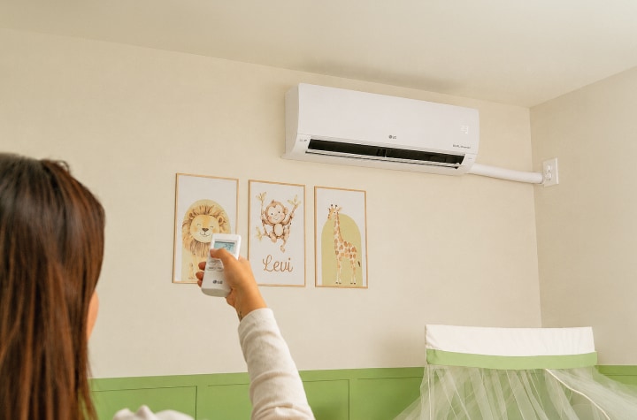 Una mamá ajusta el aire acondicionado LG de pared en la habitación del bebé.