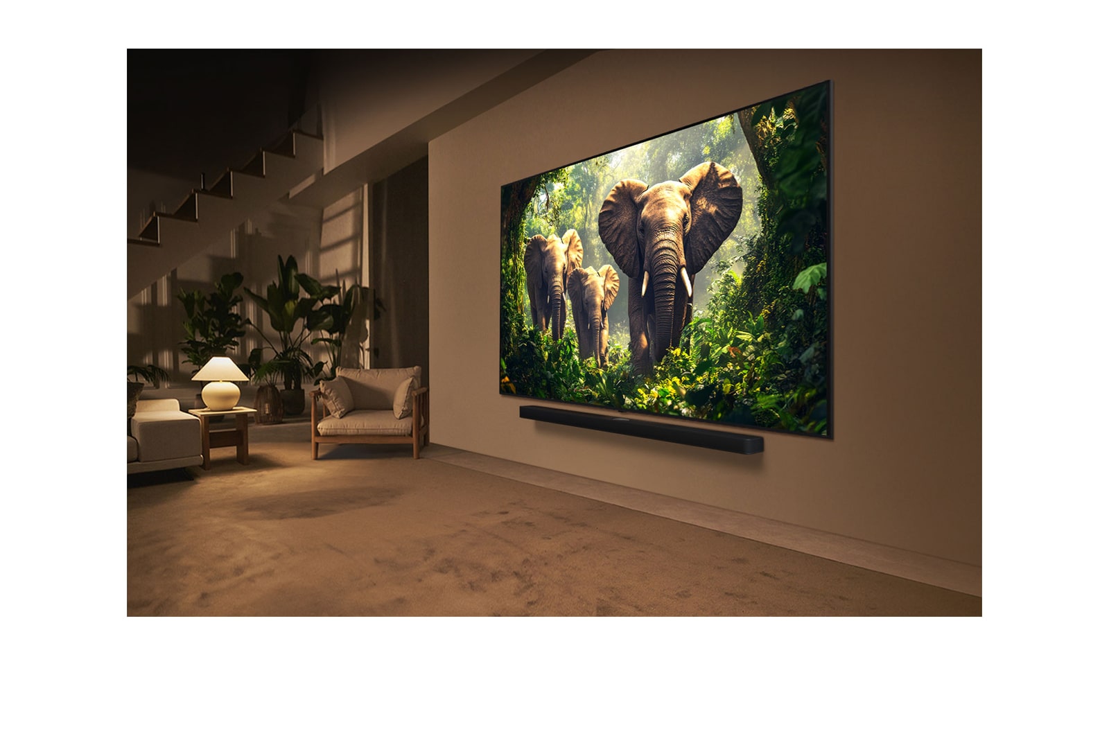 Una joven y un perro sentados frente a una LG QNED TV montada en una pared en la que se ven tres elefantes caminando hacia fuera por encima de la LG Soundbar. El título habla de cómo las escenas son más emocionantes en una pantalla gigante.