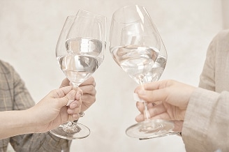  Dos personas chocando copas de vino llenas de agua cristalina, celebrando la pureza del agua.